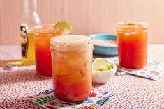 three drinks are sitting on a table with plates and utensils