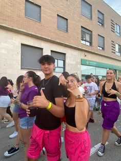 two young people standing next to each other in front of a group of people on the street