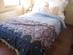 a bed sitting on top of a hard wood floor next to a window in a bedroom