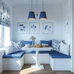 a blue and white room with two lamps hanging from the ceiling, some pillows on the bench