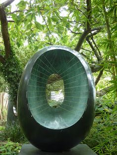 a large green sculpture sitting in the middle of a forest