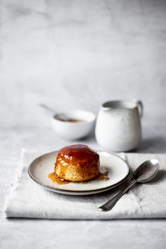 a piece of cake sitting on top of a white plate next to two silver spoons