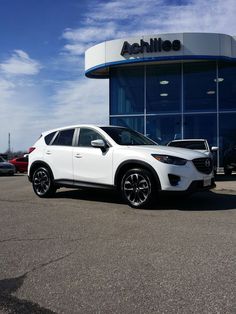 a white car is parked in front of a dealership with other cars behind it