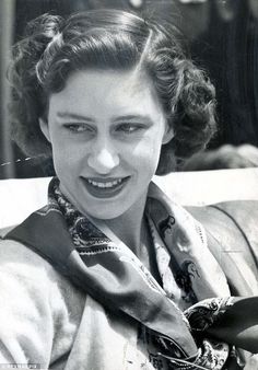 an old black and white photo of a woman with a scarf around her neck smiling