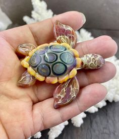 a hand holding a small glass turtle in it's palm