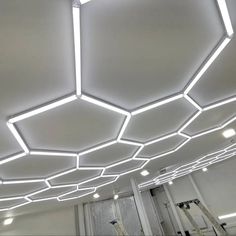 the ceiling is made up of white hexagonal tiles and has lights on each side