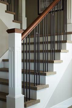 a staircase with wooden handrails and white painted walls in a home, showing the banister