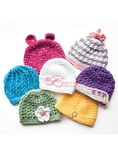 four crocheted hats with bows on them sitting next to each other in different colors