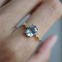 a woman's hand with a ring on it and a blue stone in the middle