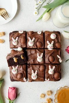 chocolate brownies with bunny ears cut into squares on a white surface next to flowers