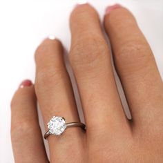 a woman's hand with a diamond ring on top of her finger, against a white background