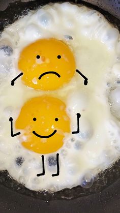 two eggs with faces drawn on them in a frying pan