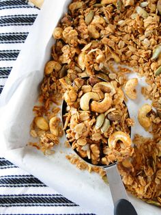 a bowl filled with granola sitting on top of a white table cloth next to a spoon