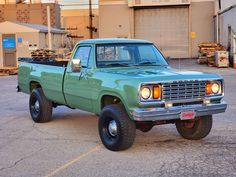 a green pick up truck parked in a parking lot