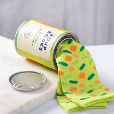 a can of soda next to a pair of socks on a white counter with a green and orange tie