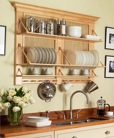 a kitchen filled with lots of dishes and cups on top of a wooden shelf above a sink