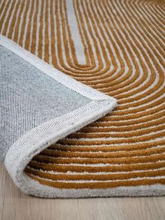 an orange and white rug on top of a wooden floor next to a black cat