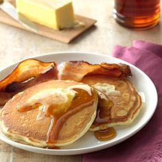 pancakes with syrup and bacon on a white plate