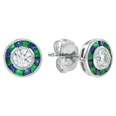 A diamond with emerald and sapphire target earrings, rub-over-set to the center with a round brilliant cut diamond surrounded by French cut emeralds and sapphires, all set in 18k white gold. A gorgeous diamond with emerald and sapphire target earrings, made in the style of Art Deco ring. Information Metal: 18K White Gold Width: 7 mm. Length: 7 mm. Weight: 3.6 g. (approx. in total) Backing: Push Back Center Gemstones Type: Diamond Shape: Round Average Color: G Average Clarity: VS Size: 3.5 mm. Nu Peacock Colors, Earring Box, French Cut, Estilo Art Deco, Art Deco Ring, Art Deco Style, Round Brilliant Cut Diamond, Deco Style, Brilliant Cut Diamond