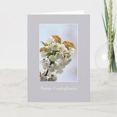 a greeting card with white flowers in front of a vase and two green plants on the side