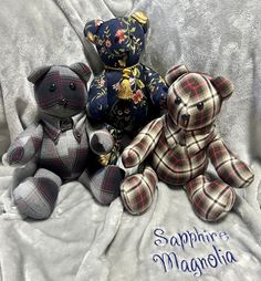 three teddy bears sitting on top of a bed covered in a blanket with the words saphirre magnania