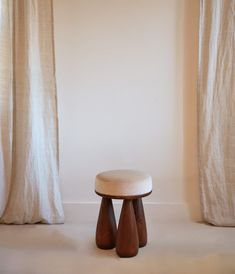 a stool sitting in front of two white curtains