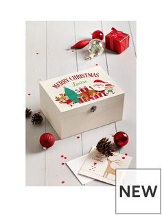 a wooden box with christmas greetings on the lid and decorations around it, including pine cones