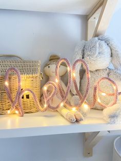 two stuffed animals sitting on top of a white shelf next to some baskets and lights