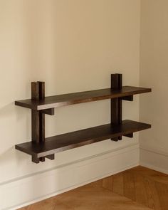 two wooden shelves on the wall in an empty room with hard wood flooring and white walls