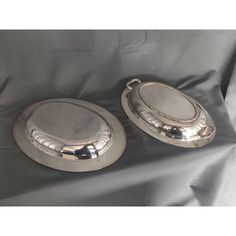 two silver plates sitting on top of a black cloth