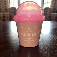 a pink ice cream cup sitting on top of a wooden table