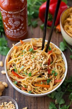 a white bowl filled with noodles and vegetables next to some chopsticks in it