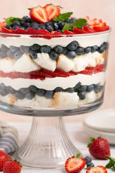 an american flag cake with strawberries and blueberries in the middle on a glass pedestal