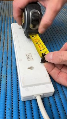 a person is using a tape to attach a light switch on a blue and white wall