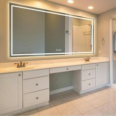 a bathroom with two sinks and a large mirror on the wall over it's counter