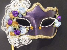 Handmade Venetian Masquerade mask covered in Purple and Gold Fabric. Eyes are outlined with pearl beading and gold rhinestones. The right side of the mask is the most elaborate part of the mask and is covered with fabric flowers in the same tones of the mask, pearls. rhinestones and lace.  It is outlined with gold trim for an exquisite finish. Can come with a ribbon covered stick to hold from or tie back ribbons. This type of mask would look lovely on any Bride for a Venetian Masquerade Wedding. Venetian Wedding, Venetian Masquerade Masks, Masquerade Wedding, Venetian Masquerade, Carnival Masks, Beautiful Mask, Masquerade Mask, Masquerade Ball, Gold Fabric