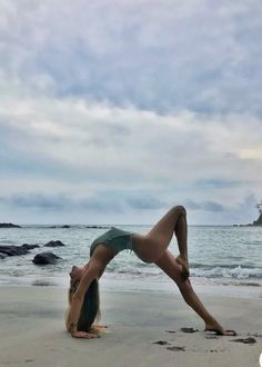 a woman doing a handstand on the beach