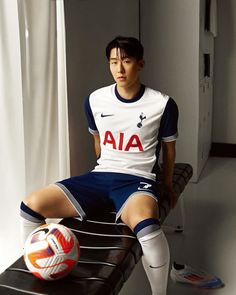 a young man sitting on top of a bench next to a soccer ball