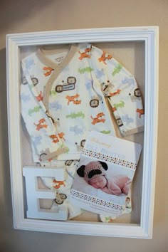 a baby's photo in a shadow box is shown with its clothes and booties