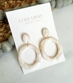 a pair of white earrings sitting on top of a card