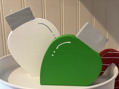 two green and white pieces of paper in a bucket on the wall next to each other