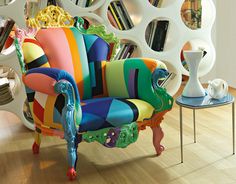 a colorful chair sitting in front of a book shelf filled with books