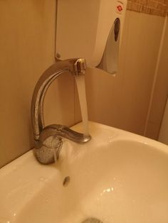 a faucet running water from a sink in a bathroom with no shower curtain