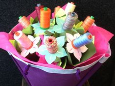 a purple basket filled with lots of colorful thread and spools