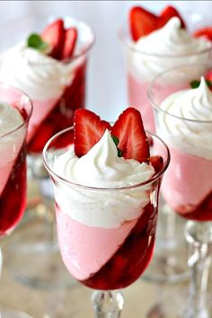 four desserts with strawberries and whipped cream in small glasses on a silver tray