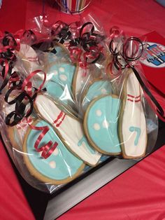 some decorated cookies in plastic bags on a red table with glasses and ribbon around them