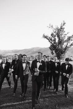 a group of men in tuxedos walking across a field