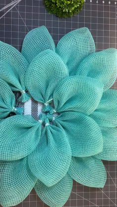 a flower made out of mesh sitting on top of a cutting board next to scissors