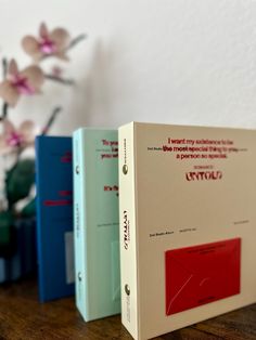 three books sitting on top of a table next to a vase with flowers in it