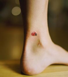 a ladybug tattoo on the foot of a woman's left leg is shown